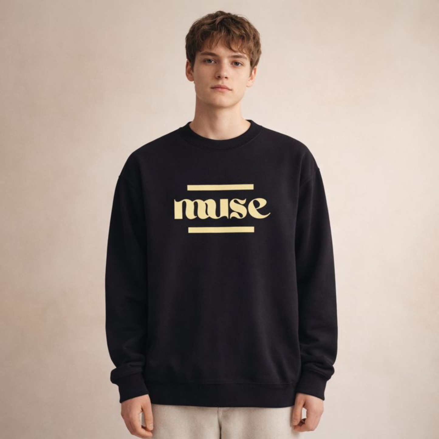 Black unisex crewneck sweatshirt featuring “muse” minimal typography, studio front view on warm beige background.