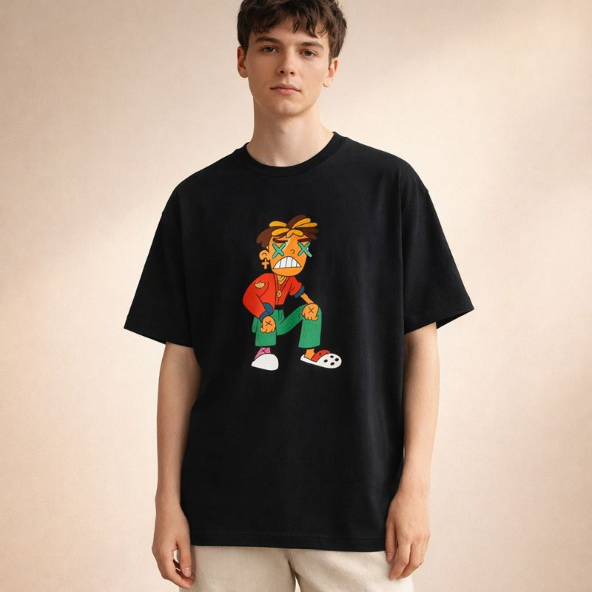 Black oversized streetwear tee with vivid cartoon figure print, modeled front-facing in softly lit cream studio backdrop