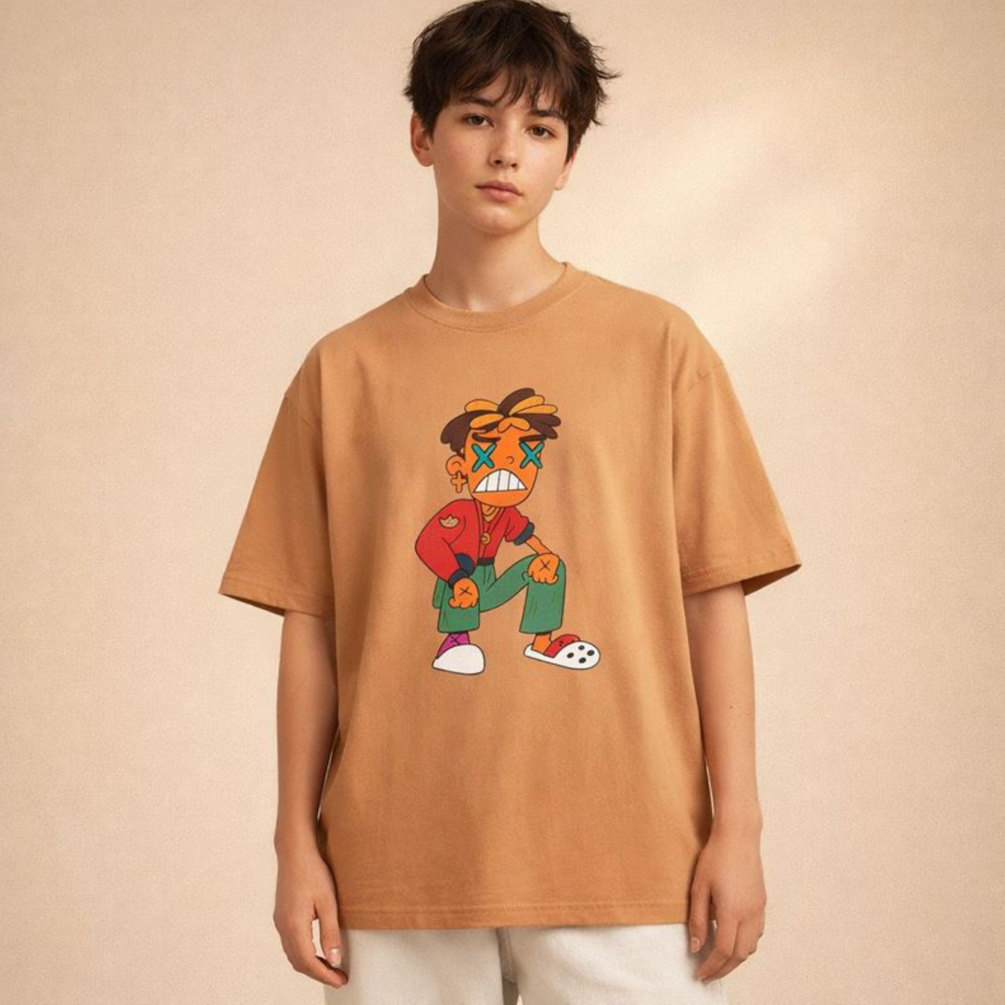 Warm tan oversized t-shirt with playful cartoon illustration, worn by androgynous model in softly toned studio setting